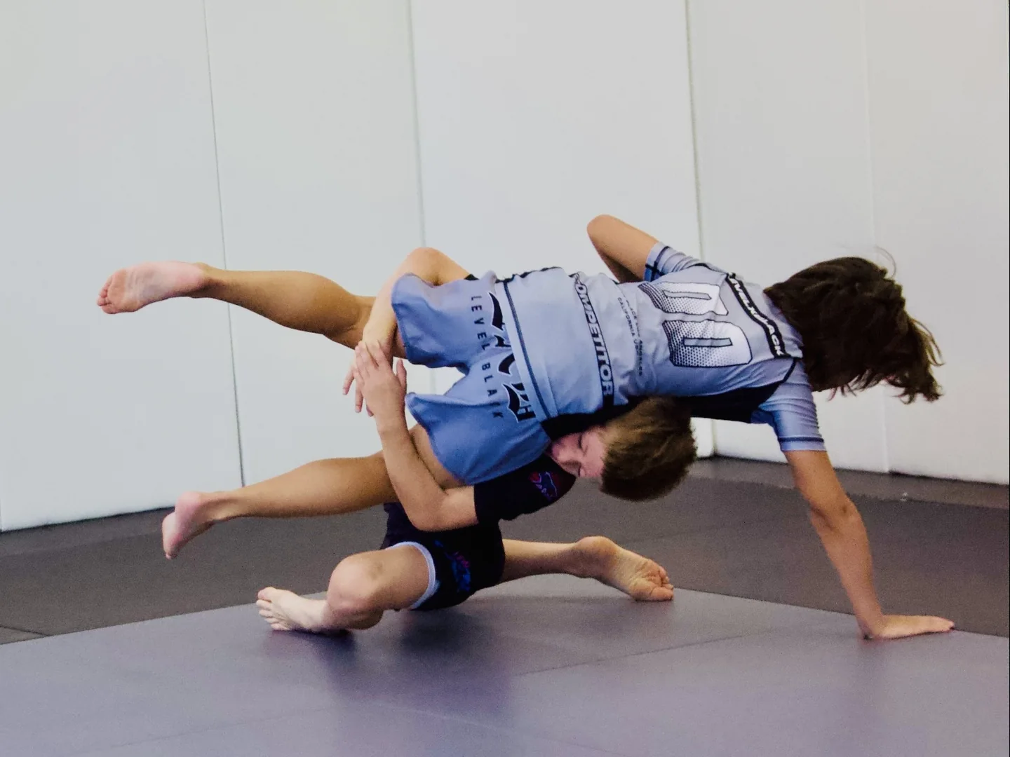 Deux jeunes pratiquent le jiu-jitsu sur les tatamis.